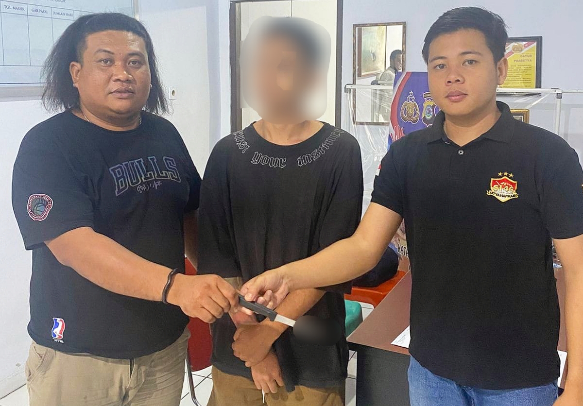 Terduga pelaku AT diapit dua personel Polres Bitung. (Foto: Istimewa)