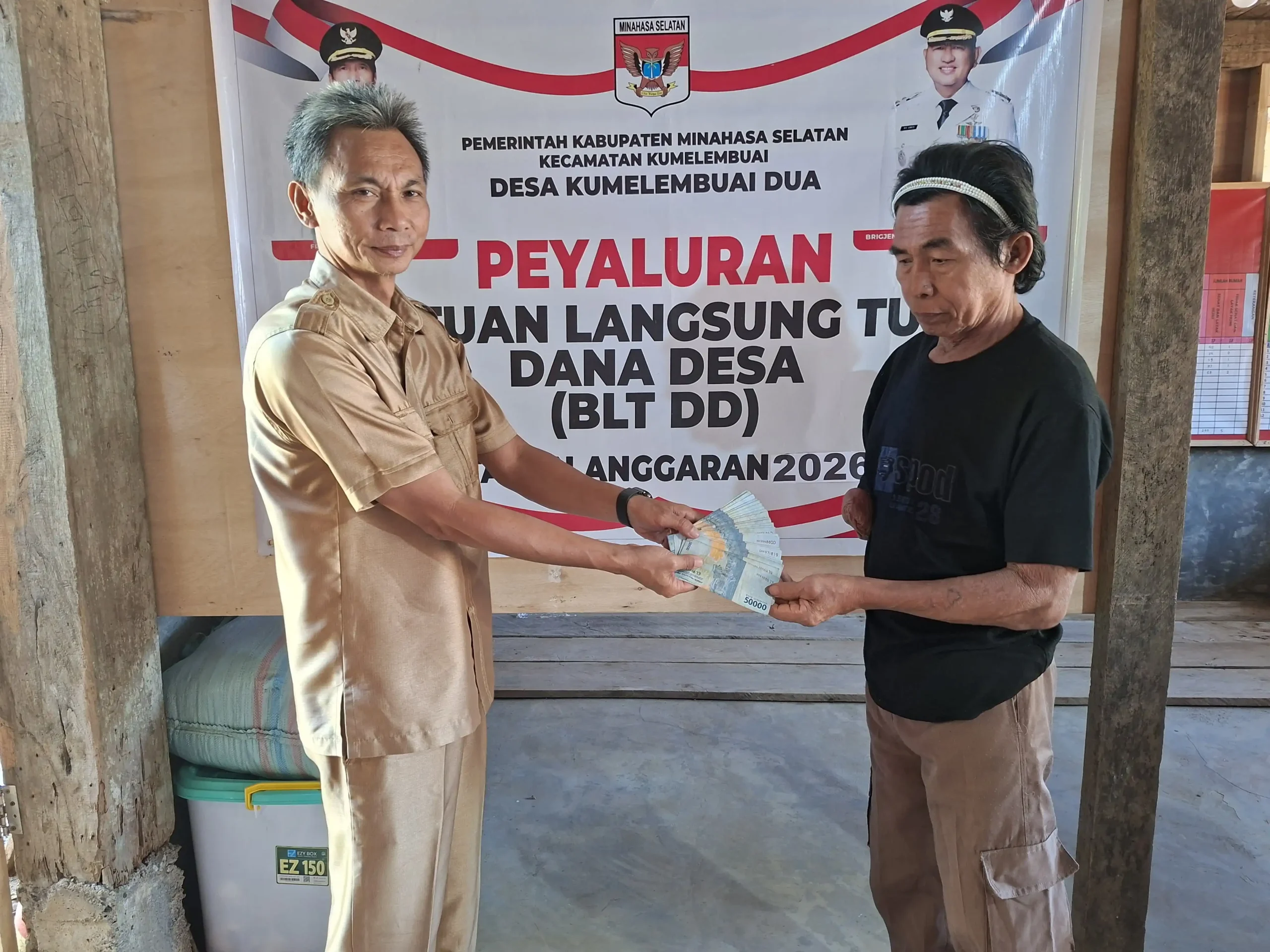 Hukum Tua Desa Kumelembuai Dua Stevan Polla SIP saat menyerahkan bantuan sosial.