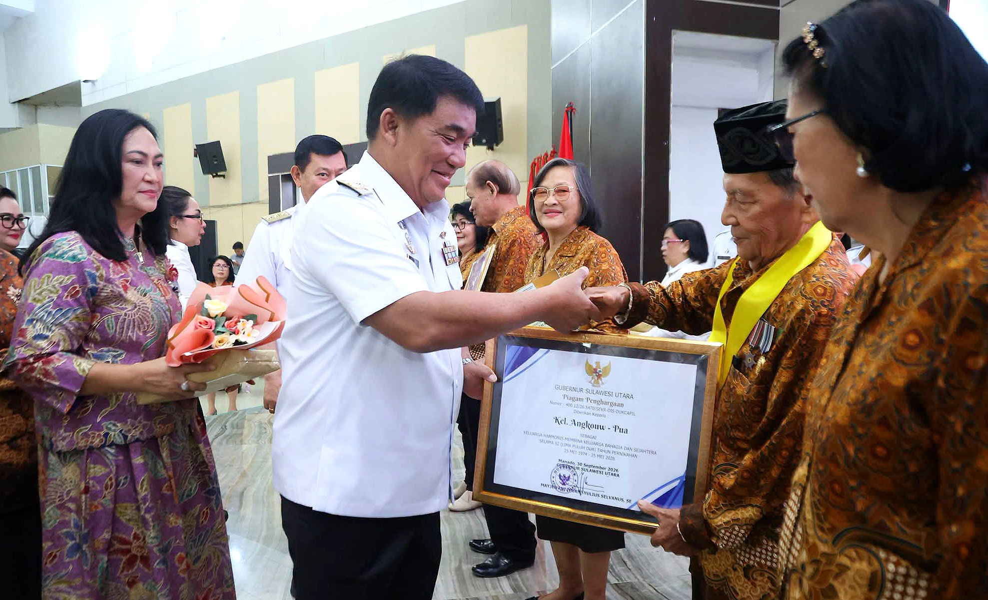 Gubernur Sulawesi Utara Mayjen TNI (Purn) Yulius Selvanus SE didampingi Ketua TP PKK Ny. Anik Yulius Selvanus menyerahkan penghargaan kepada pasangan keluarga harmonis di HUT ke-64 PWRI, Rabu (7/10/2026). (Foto: Istimewa)