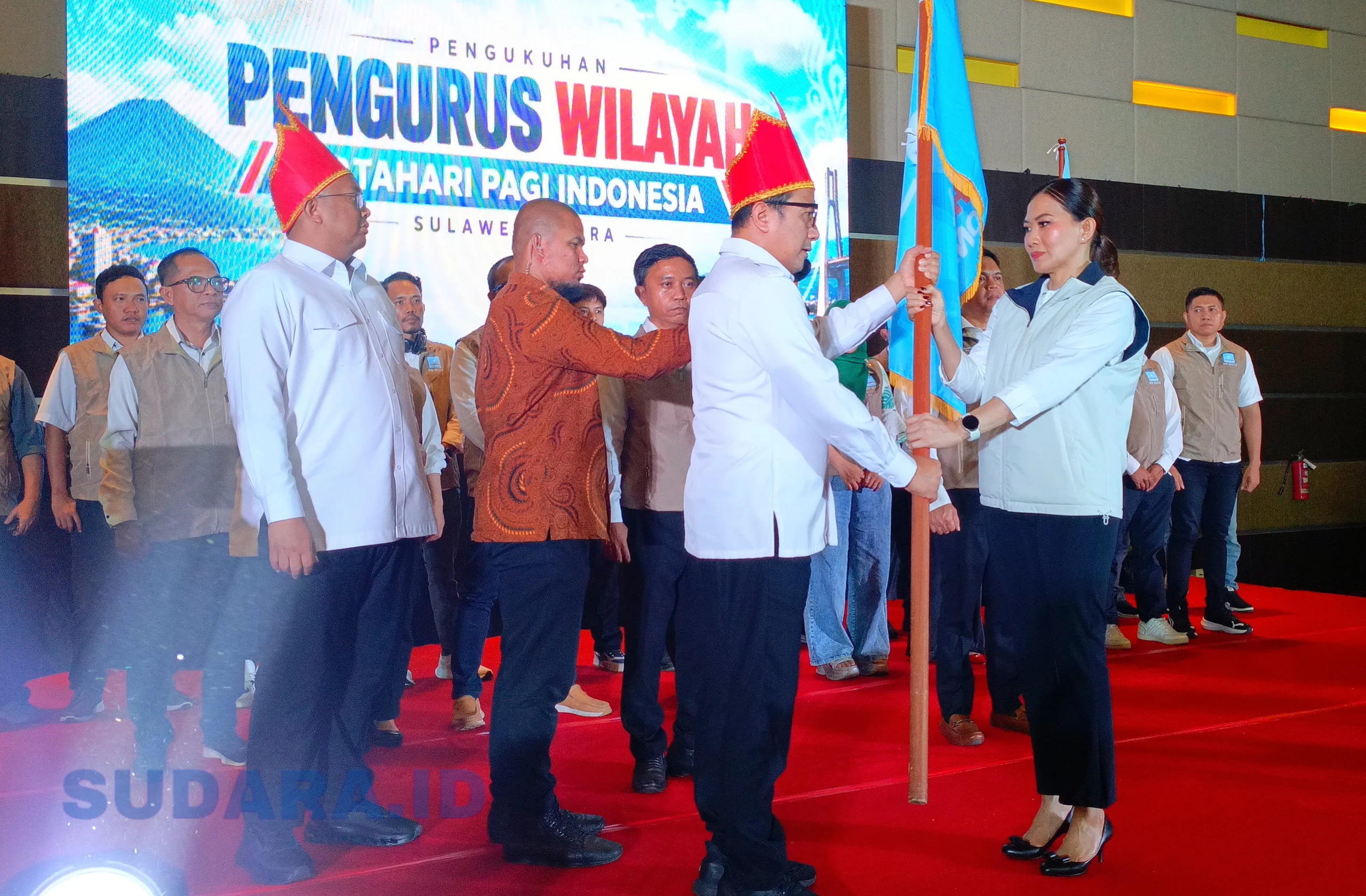 Ketum PB MPI, Dr. Sutia Budi, menyerahkan panji pataka kepada Ketua PW MPI Sulawesi Utara, Theresia Inggrid Manangka, dalam prosesi pengukuhan di Manado, Jumat (30/10/2026). Panji organisasi resmi dikibarkan untuk membumikan gerakan sosial dan kebudayaan di Bumi Nyiur Melambai. (Foto: Ridho L Tobing)
